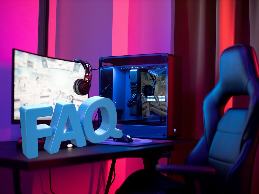 Gaming desk with LED lights, large monitor, PC case, and blue 3D “FAQ” letters in front of the screen.